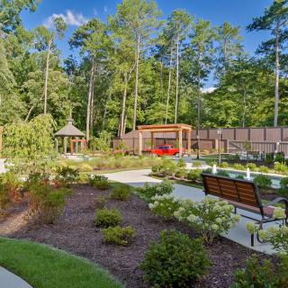 A beautifully landscaped garden with a pathway, benches, and a gazebo surrounded by lush greenery.