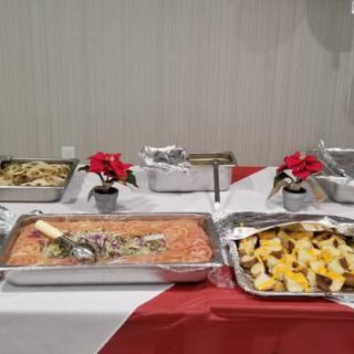 A buffet table with a variety of dishes, including pasta and salad, arranged in trays.
