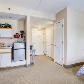 A compact apartment with a kitchenette and hallway leading to multiple doors.