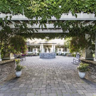 A serene courtyard featuring a central fountain surrounded by lush greenery and patio seating.