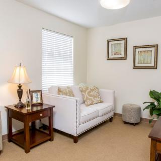 A cozy living room with a white sofa, side table, lamp, and decorative artwork.