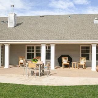 A backyard patio with outdoor furniture and a well-maintained lawn.