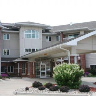 A modern residential building with a covered entrance and landscaped surroundings.