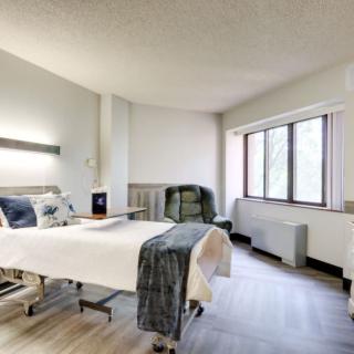 A clean and well-lit hospital room with a bed and large window.