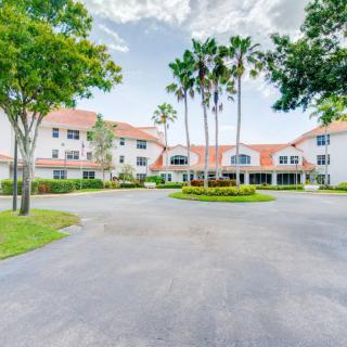 A residential building with palm trees and a circular driveway on a clear day.