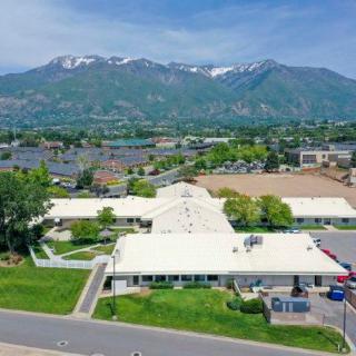An aerial view of a building with a mountainous backdrop in a suburban setting.