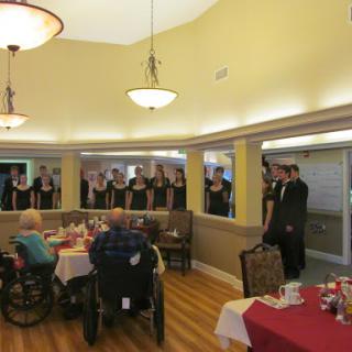 A choir performs for residents in a senior living community, creating a joyful atmosphere.
