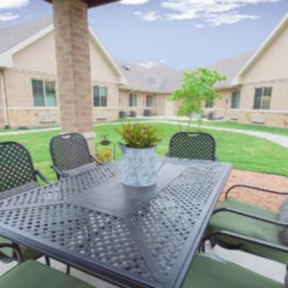 A patio with an outdoor table and chairs overlooking a landscaped courtyard.