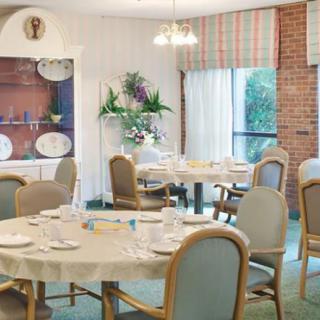 An elegant dining room with round tables and cushioned chairs, set for a meal.