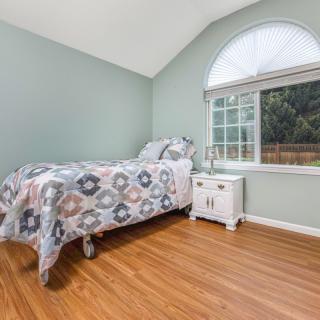 A cozy bedroom with a single bed and a large arched window.