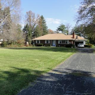 A suburban house with a large lawn and a driveway leading up to it.