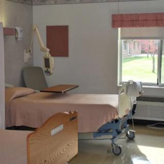 A hospital room with a bed and medical equipment near a window.