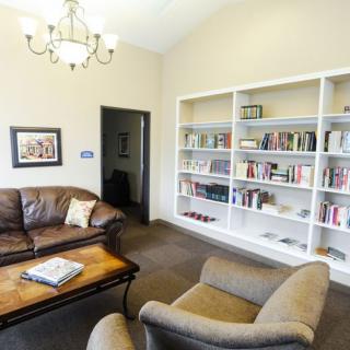 A cozy living room with a couch, armchairs, and a large bookshelf.