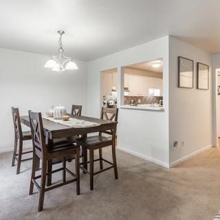 A modern dining area with a wooden table and high chairs, featuring an open layout.
