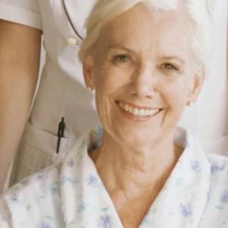An elderly woman smiling indoors.