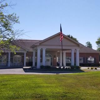 A building with a front entrance featuring columns and a flagpole in the foreground.