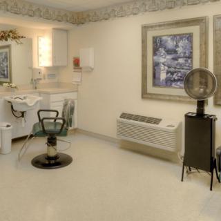 An empty hair salon with a styling chair and hair dryer set against a neatly decorated interior.