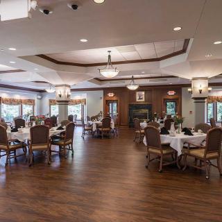 An elegant and spacious dining room with neatly arranged tables and chairs, adorned with warm lighting.