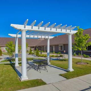 A pergola with outdoor seating in a landscaped garden area.