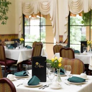 An elegantly set restaurant dining area with neatly arranged tables and chairs, featuring decorative curtains and a serene ambiance.