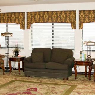 A cozy living room with a dark sofa, patterned rug, and elegant window treatments.