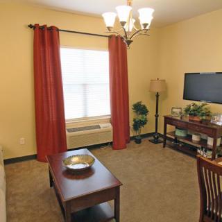 A cozy living room with a television, red curtains, and a coffee table.