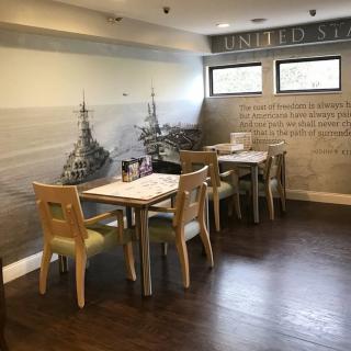 A cozy restaurant interior with neatly arranged tables and chairs, featuring artistic wall decor.