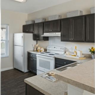 A modern kitchen with dark cabinets and white appliances.