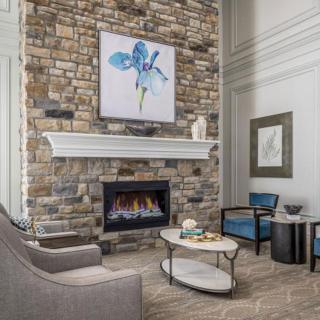 A modern living room featuring a stone wall with a fireplace, complemented by contemporary furniture and artwork.