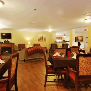 A cozy dining room with several tables and chairs, warm lighting, and tasteful decor.