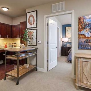 A cozy apartment interior showcasing a kitchen area with rich wooden cabinets and a hallway leading to a bedroom.
