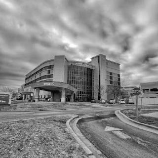 A modern architectural structure captured in black and white under a dramatic cloudy sky.