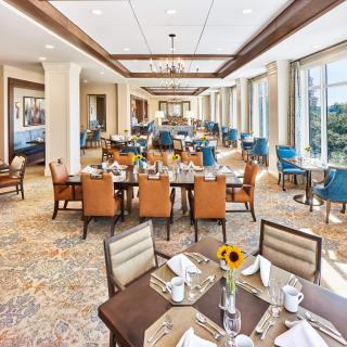 An elegant dining room with neatly arranged tables and chairs, featuring large windows and stylish decor.