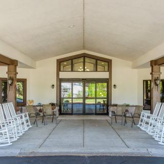The entrance of a building features rocking chairs on a spacious porch.