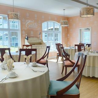An elegant dining room with round tables, wooden chairs, and soft lighting.