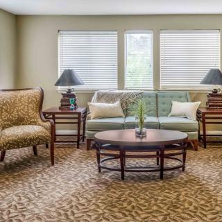 A cozy living room with a sofa, armchairs, and a coffee table surrounded by warm lighting.