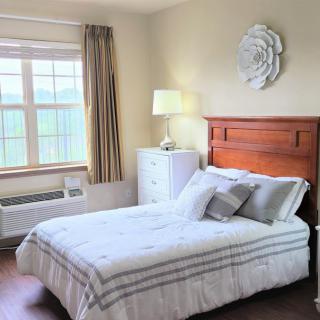 A cozy bedroom with a neatly made bed, large window, and stylish decor.