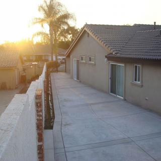 A residential house with a paved driveway during sunset, featuring a palm tree in the background.