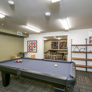 A modern game room featuring a pool table, seating area, and decorative shelving.