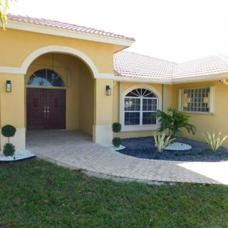 A beautiful yellow house with a well-maintained front yard and an inviting entrance.