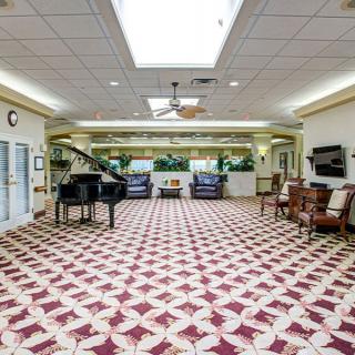 A spacious and well-lit lobby with a piano, ample seating, and decorative tile flooring.
