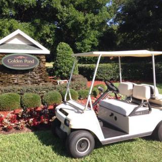 A golf cart parked in front of a landscaped area with a sign reading 'Garden Park'.