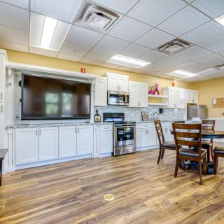 A modern kitchen with white cabinetry, a dining table, and various appliances.