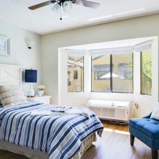 A bright and modern bedroom with a striped bedspread and large window.