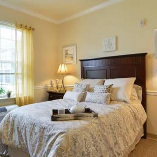 A cozy bedroom with a neatly made bed and warm lighting.