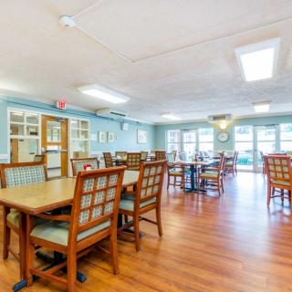 A spacious and well-lit dining area with wooden tables and chairs arranged neatly.