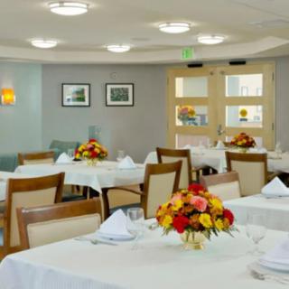A well-decorated dining room with neatly arranged tables and floral centerpieces.