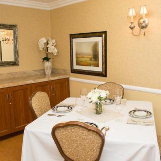 A neatly set dining table with elegant decor, featuring flowers and artwork on the wall.