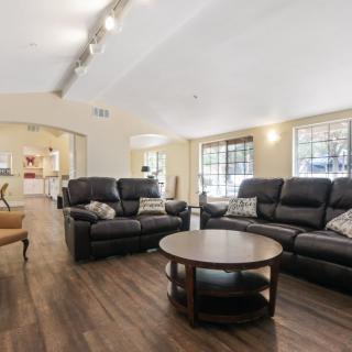 A spacious and modern living room featuring comfortable leather sofas, a round coffee table, and large windows that allow natural light to fill the space.