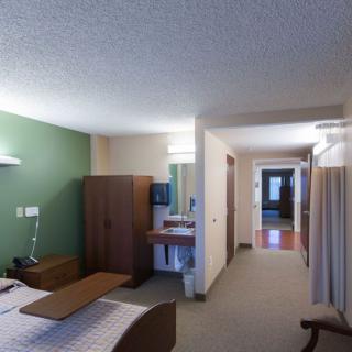 A modern and comfortable hotel room interior with a bed, wardrobe, and a small desk area.